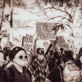 A person at a protest holding a board that says "Abolish Prisons"
