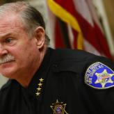 A man with white hair and white mustache in a sheriff's uniform.